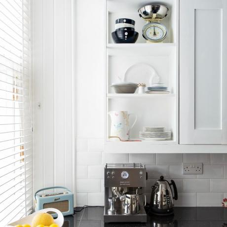 Белая кухня с серебристой кофемашиной и чайником.