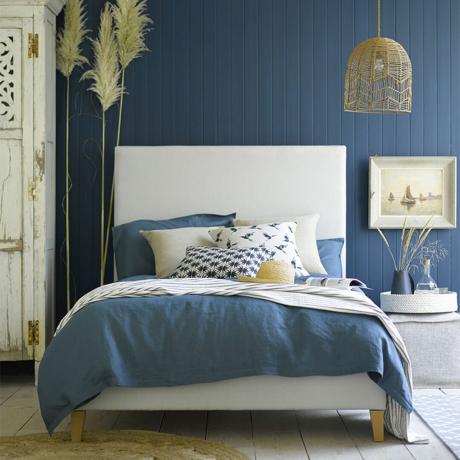 Dormitor albastru cu pereți lambriuri albaștri și lenjerie de pat din denim