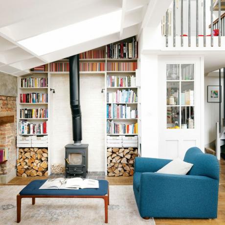 blauwe fauteuil in leefruimte met open haard en boekenplanken