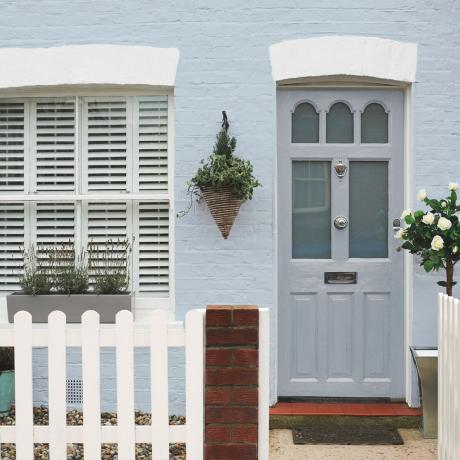 kesalahan warna pintu depan, eksterior bergaya cottage dengan pintu depan abu-abu pucat, dinding luar bercat biru, aksen putih, pagar kayu putih