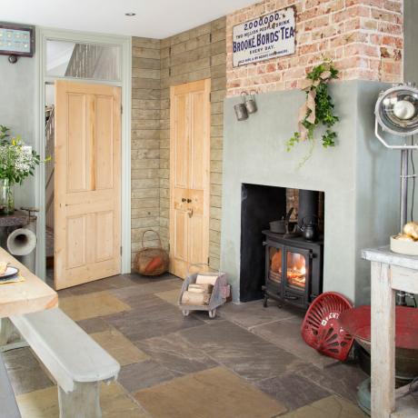 En spisestue i et åpent kjøkken med steinfliser av varierende størrelse på gulv med antikt og vintage tilbehør - David Giles