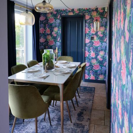 Jadalnia ozdobiona różową i niebieską kwiecistą tapetą ze stołem jadalnym i zielonymi krzesłami