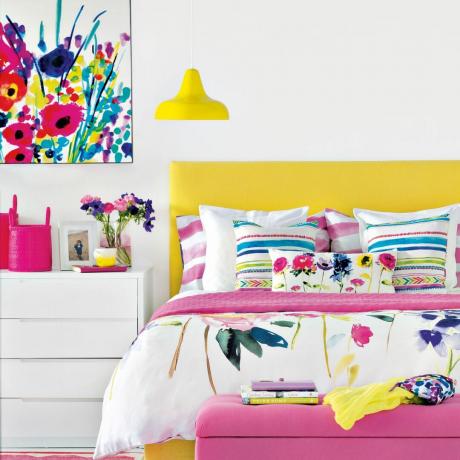kamar tidur berwarna cerah dengan pola bunga kuning dan merah muda