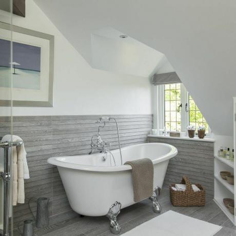 حمام بأرضية خشبية رمادية اللون وإطار للصور على جدار أبيض