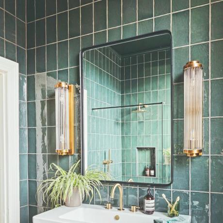 Salle de bain carrelée avec miroir et lavabo