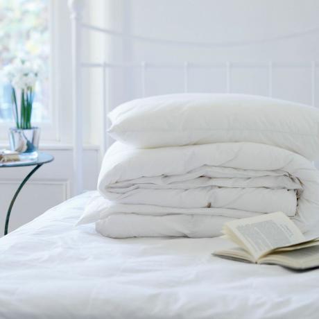 Hvitt sengetøy på toppen av madrassen