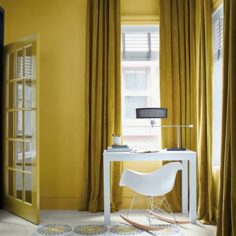 ідеї кольору плінтуса, жовтий домашній офіс з жовтими плінтусами, жовті штори, білий стіл і стілець, ретро-килим, біла підлога