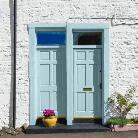 Dvi mėlynos spalvos lauko durys baltuose kotedžuose