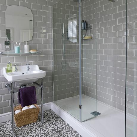 Vonios kambarys su sulankstoma vonia ir raštuotomis grindų plytelėmis