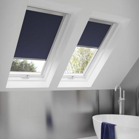 حمام ذو سقف مائل مع نوافذ من طراز velux وستائر معتمة باللون الأزرق الداكن
