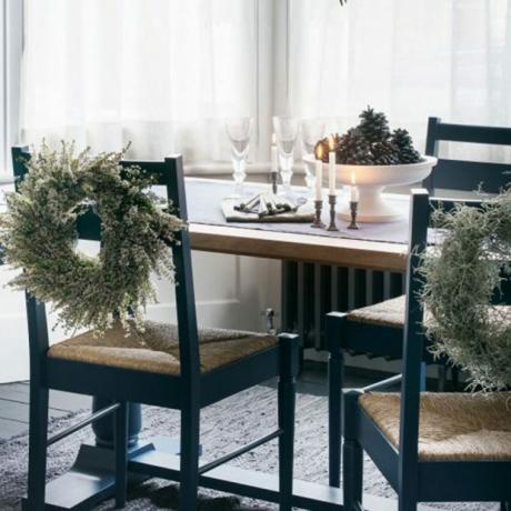 Tummansininen ruokapöytä ja tuolit valkoisilla tuoliseppeleillä