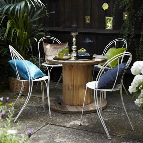 حديقة مع طاولة أسطوانة مستديرة وكراسي معدنية