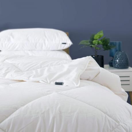 Dormitor albastru cu pat alb și plapumă pliată pe spate