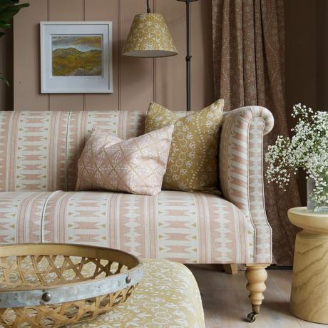 sala de estar beige y crema de inspiración costera con sofá a rayas y lámpara de pared