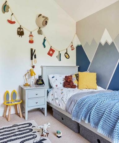 quarto infantil com cena de montanha pintada na parede, bandeirola e arte de parede com cabeça de animal