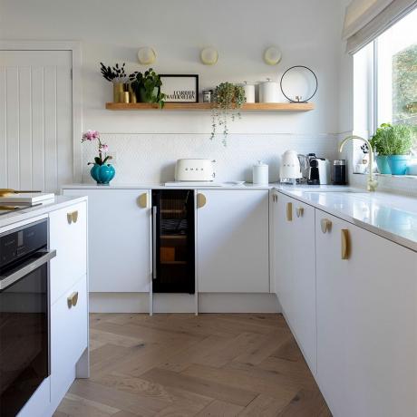 balta virtuvė su sala ir medine lentyna bei silkės grindimis