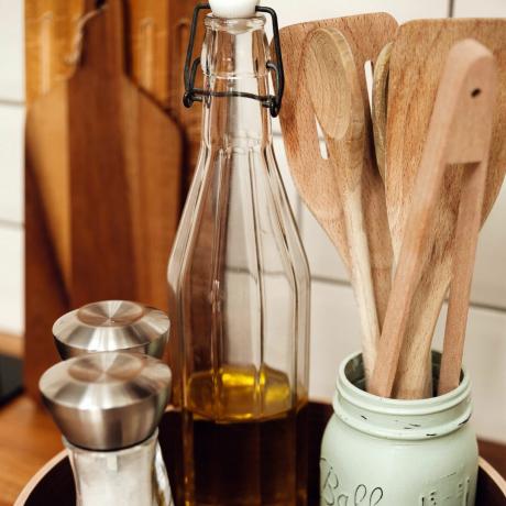 Variedade de utensílios de madeira em vaso no balcão da cozinha ao lado da garrafa de vidro