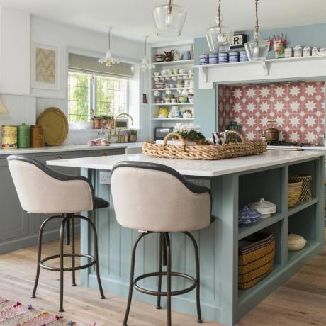 ห้องครัวสีฟ้าพร้อมโต๊ะเตรียมอาหารและเก้าอี้สตูลสีชมพู