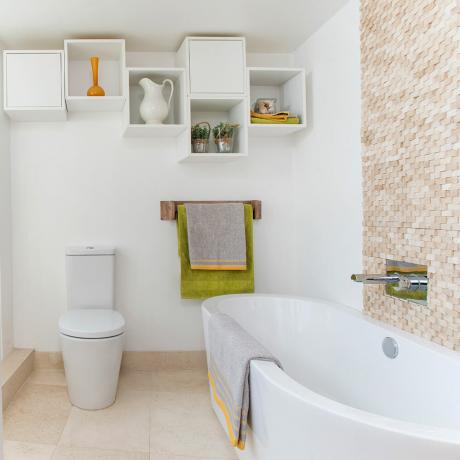 Valkoinen kylpyhuoneen uudistus, jossa on erillinen kylpyamme ja kaakeloitu paneeli
