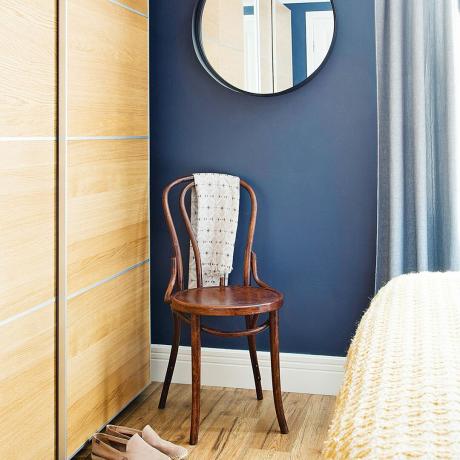 ワードローブのスライドドアと木製の椅子を備えたネイビーブルーのベッドルーム