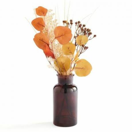 Un jarrón marrón lleno de flores artificiales otoñales.