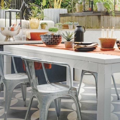 espace de vie extérieur avec cuisine extérieure, table, chaises en métal, carrelage à motifs