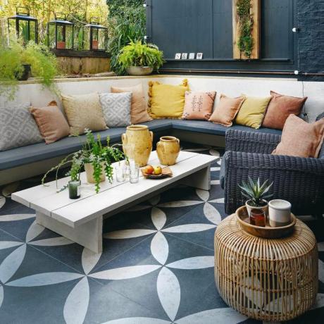 trädgård uteplats med mönstrade golvklinker och inbyggd soffa med lågt soffbord