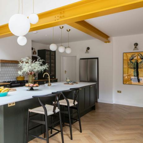 Otevřená kuchyně se žlutými ocelovými trámy a lednicí s mrazničkou v americkém stylu