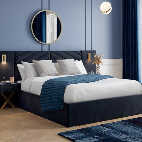 Cama doble con ropa de cama blanca y azul en el dormitorio de tono azul