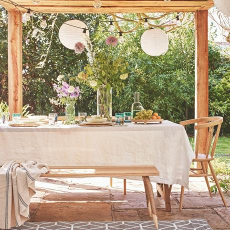 açık hava yemek bahçe partisi masa düzeni, keten masa örtüsü, masada çiçekler, bank, battaniye, kilim, pergola
